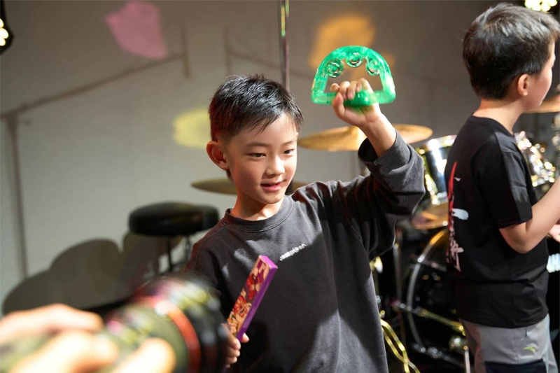 ステージでタンバリンを持って演奏する男の子